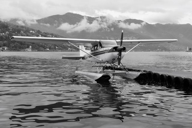 Hidroavión del Aero Club Como sobre plataforma flotante con montañas nubladas al fondo