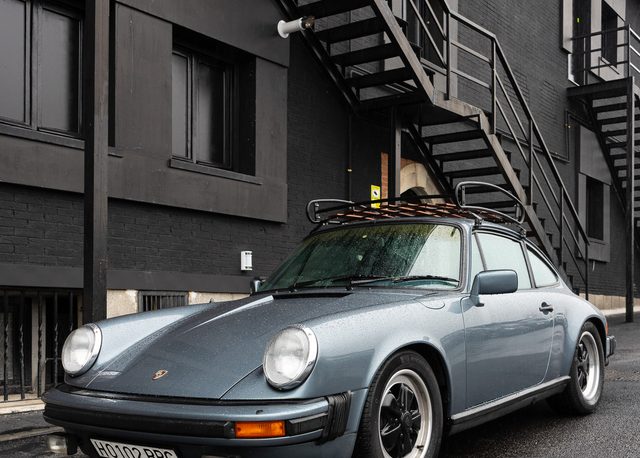 Porsche clásico con gotas de lluvia sobre la carrocería en una calle mojada de Madrid