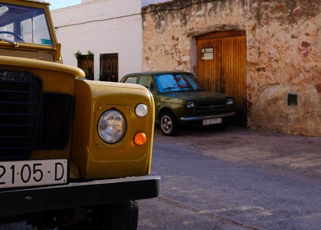 Land Rover Santana amarillo y Seat 127 verde en una calle de piedra de Vilafamés