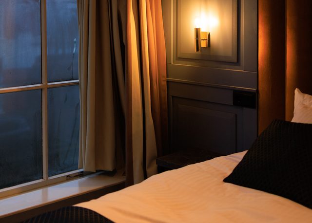 Interior de habitación del hotel The Royal Bridges en Delft con lámpara encendida y ventana empañada