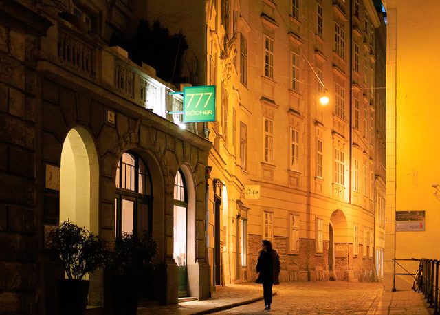 Calle histórica de Viena iluminada por farolas doradas con un caminante solitario