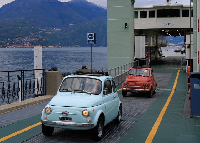 Dos Fiat 500 clásicos, azul y rojo, descendiendo del ferry en Bellagio, Lago de Como