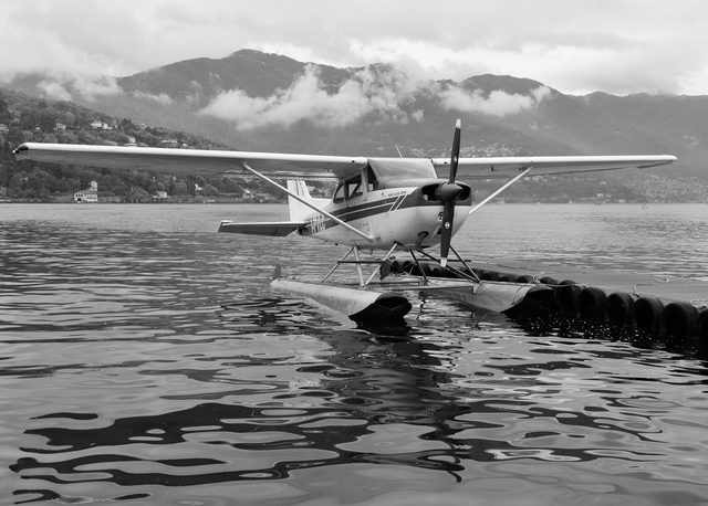 Hidroavión del Aero Club Como sobre plataforma flotante con montañas nubladas al fondo