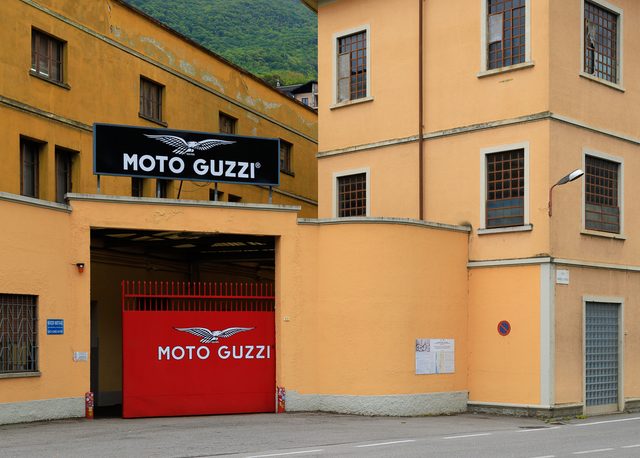 Entrada del Museo Moto Guzzi con portón rojo y logotipo alado en Mandello del Lario