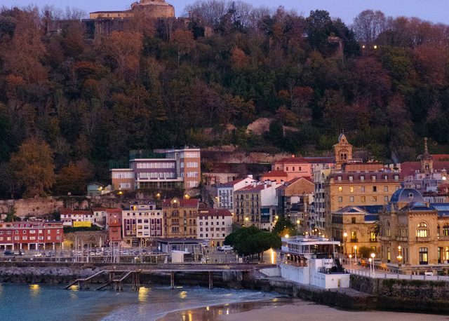 Bahía de La Concha al amanecer con el monte Urgull y arena húmeda en San Sebastián
