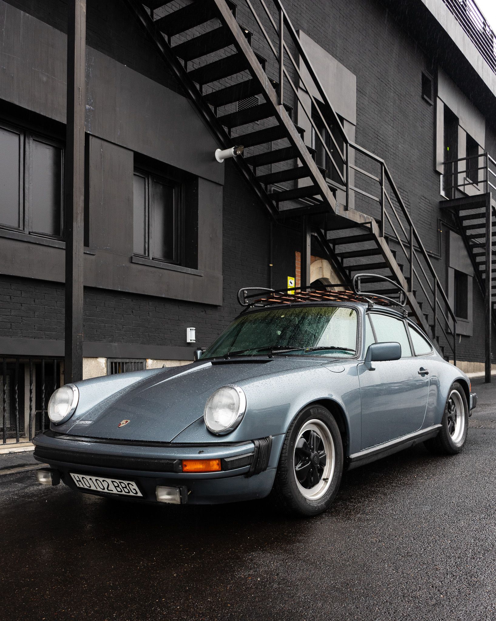 Porsche clásico con gotas de lluvia sobre la carrocería en una calle mojada de Madrid
